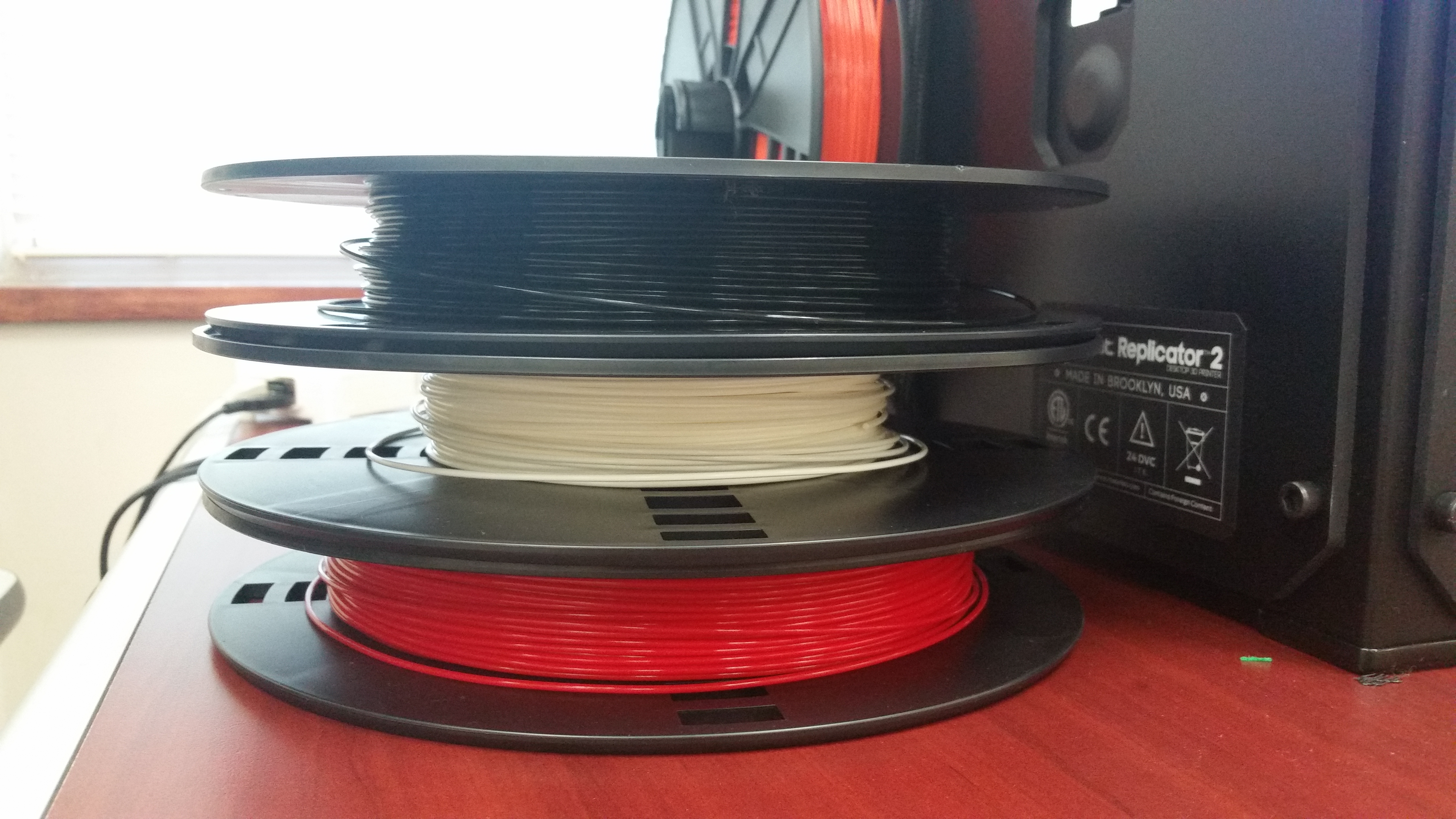stack of 3D printer filament rolls--red, white, black